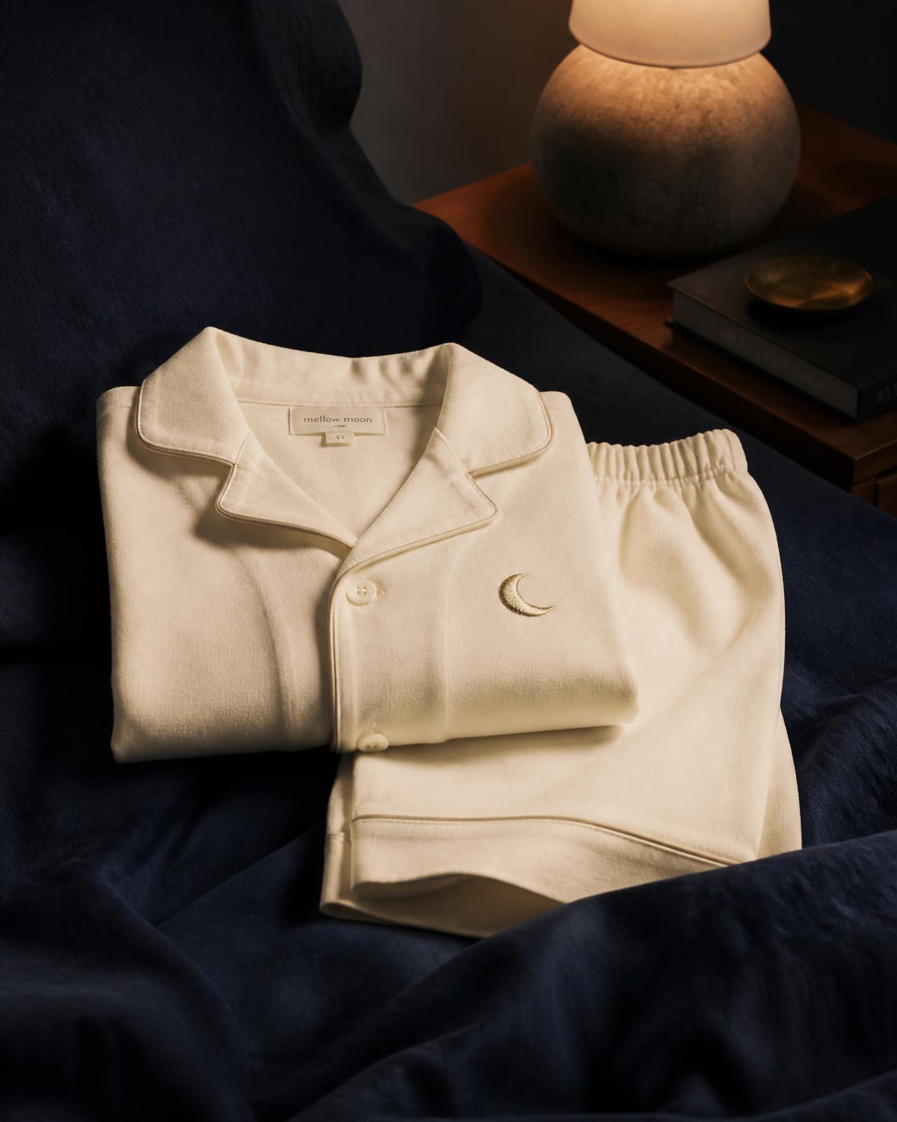 A neatly folded pair of premium cream children's pyjamas on navy linen